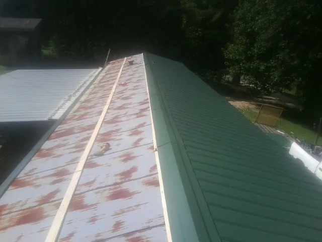 Old rusted panels beside newly installed green metal roofing — Wind Damage Roof Repair by Roofing Brothers in Coulter