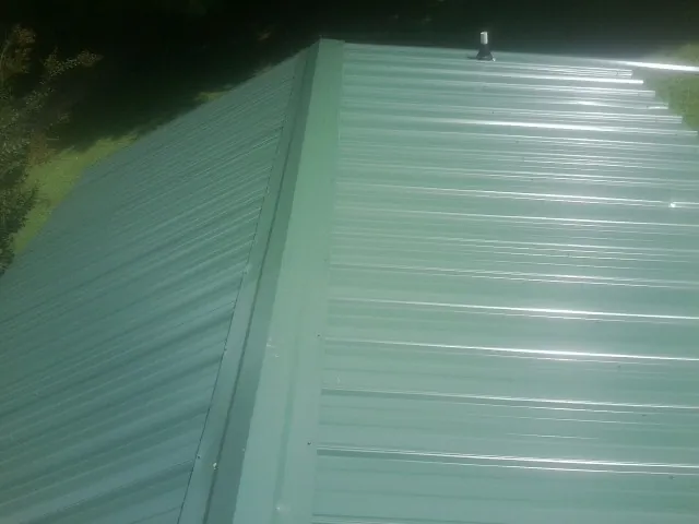 New green metal panels meeting at the ridge of a roof — Flat Roof Repair work by our crew in Coulter