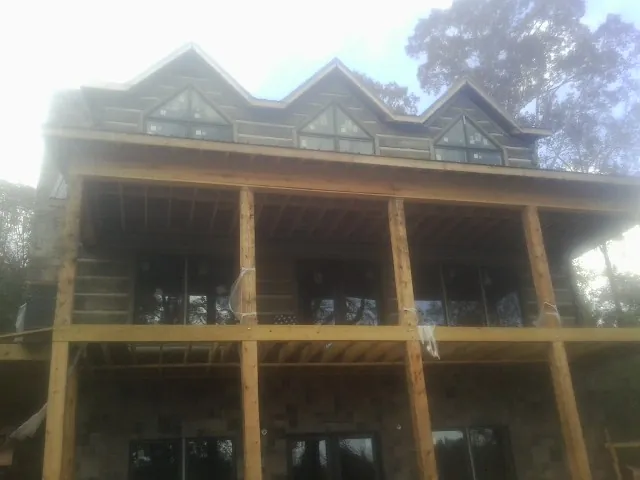 Dormers and porch framing on a large log home under construction — Roof Coating work by our crew in Coulter