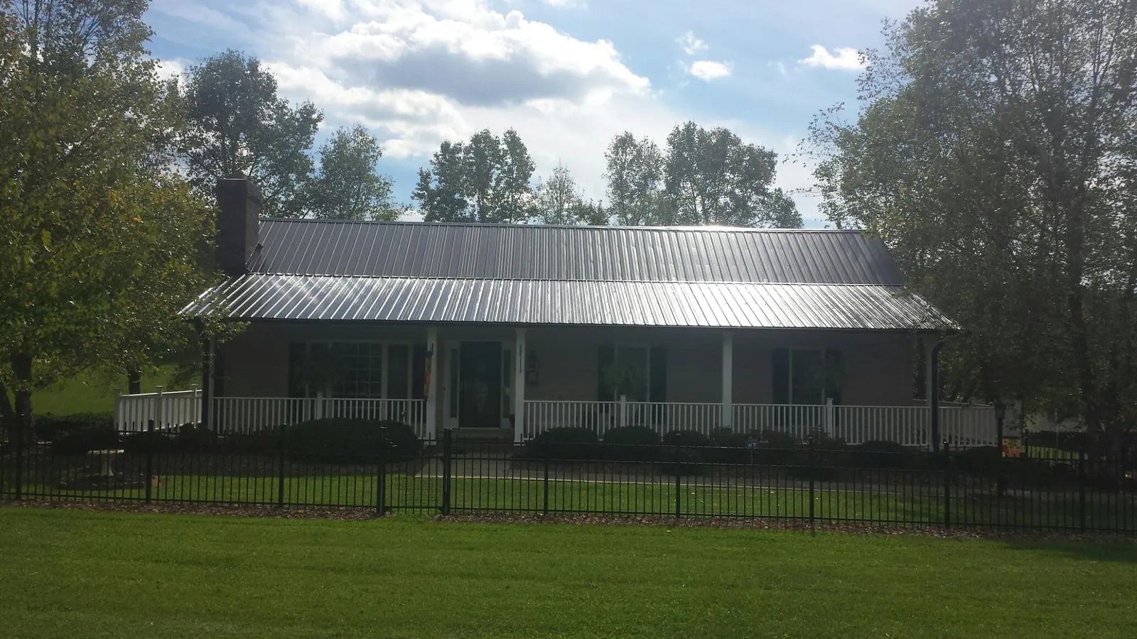 Gray metal roof on a brick ranch with a full width front porch — Gutter Guard Installation work by our crew in Coulter