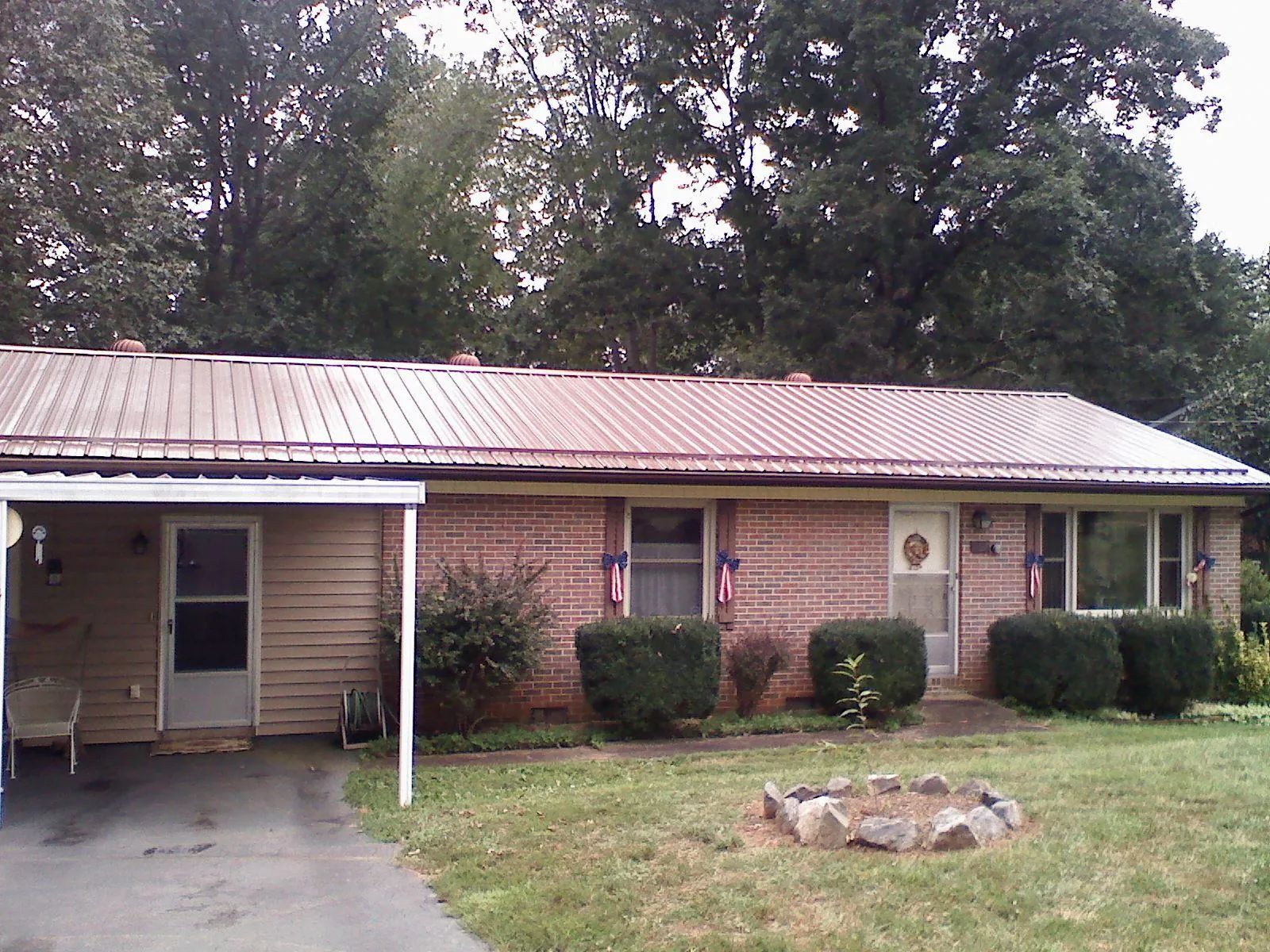 Bronze metal roof and carport on a brick ranch home — Roof Repair work by our crew in Coulter