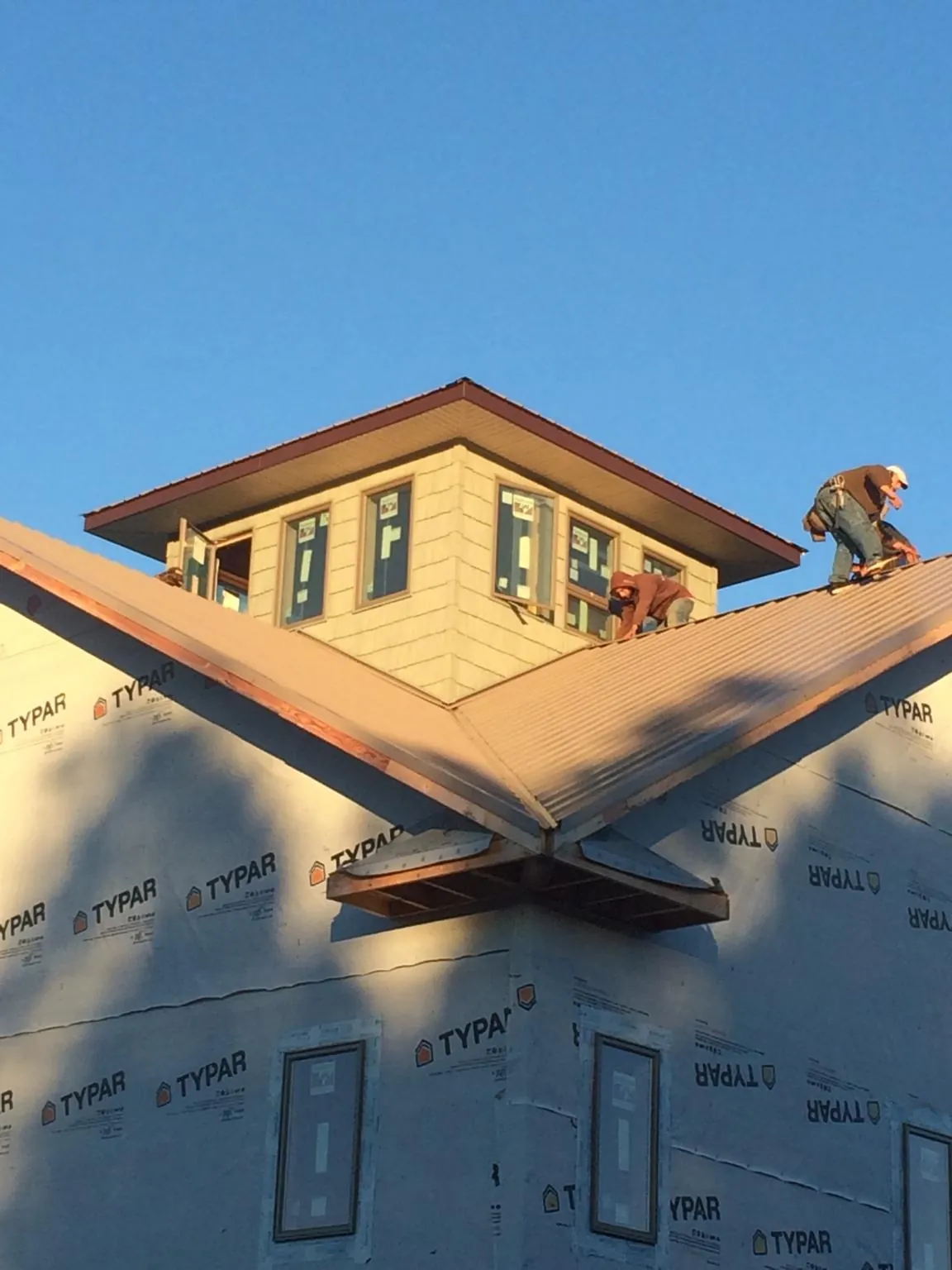 Roofers working around a rooftop cupola on a new metal roof at sunset — Roof Waterproofing in Coulter by Roofing Brothers